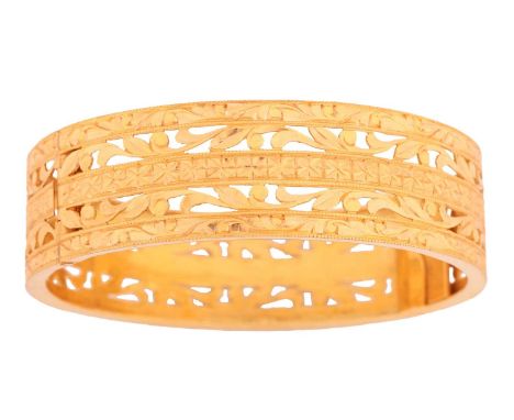 A hinged bangle of pierced scrollwork design with bright-cut patterns, to a concealed tongue clasp and figure-of-eight safety