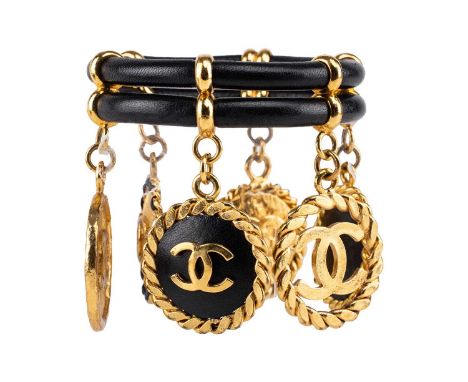 Chanel - a 1992 padded black leather bangle, dangling with six Cocomark circular charms, plaque signs '29', internal circumfe