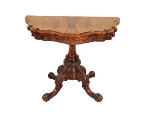 A VICTORIAN FIGURED WALNUT FOLDING CARD TABLE, Circa 1865, the demi-lune top with serpentine moulded edging, opening as a cir