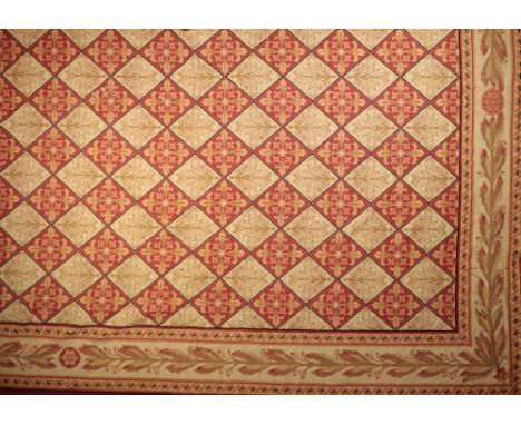AUBUSSON STYLE CARPET of late Louis XVI design, the ivory and red ground trellis field enclosing flower head motifs, a laurel