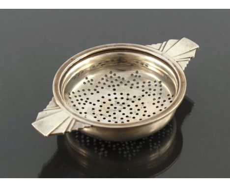 An Art Deco silver tea strainer, Walker and Hall, Birmingham 1936, ogee circular bowl with cast stepped geometric bracket han