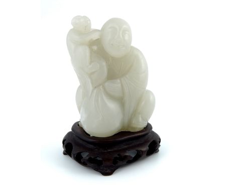 A Chinese pale jade carving, in the form of a smiling man with a monkey upon his shoulder, 6.5cm high, on a hardwood stand