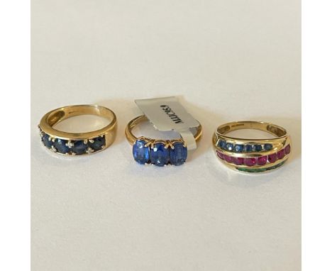 A collection of three 9ct yellow gold gem set rings. Featuring an emerald, ruby and sapphire dress ring, size Q; a Kyanite tr