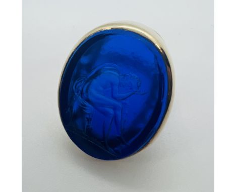 A 19th century moulded paste intaglio seal set into a 1960s cocktail ring mount.  Depicting an ancient Greek man , holding a 