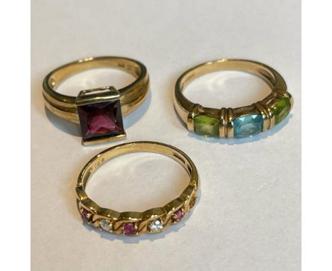 A group of 9ct gold gem set rings. Featuring a square cut garnet ring, a topaz and peridot ring and a diamond and ruby dress 