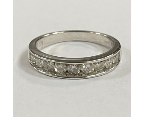 A diamond set 9ct white gold half eternity ring. Featuring nine round brilliant cut diamonds, with a central stone of an esti