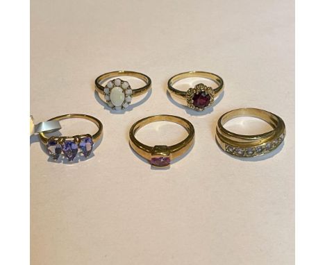 A group of five 9ct gold gem set rings. Featuring a tanzanite set band ring; a pear drop Tanzanite trilogy ring; an opal clus