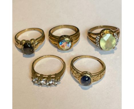 A collection of five 9ct yellow gold gem set rings. To include a cabochon sapphire ring, a black star sapphire ring, a Cubic 