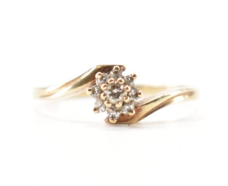 A hallmarked 9ct yellow gold & diamond crossover ring. The ring having a cluster of round cut prong basket set diamond in the