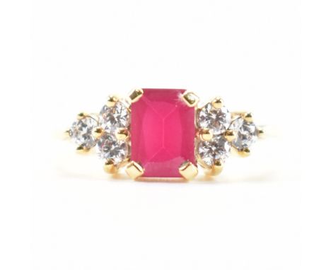 A hallmarked 9ct gold synthetic ruby and cubic zirconia CZ ring. The ring set with a mixed cut synthetic ruby flanked by thre