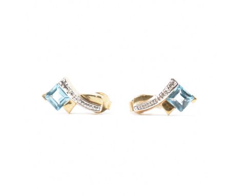 A pair of 9ct yellow gold, topaz &amp; diamond stud earring. The earrings having a crossover style head set with accent round