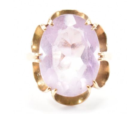 A hallmarked 9ct gold and amethyst cocktail ring. The ring set with a large oval cut 17.8mm x 13mm x 7.5mm. having decorative