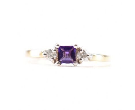 A hallmarked amethyst and diamond three stone ring. The ring set with a square step cut amethyst flanked by two round brillia