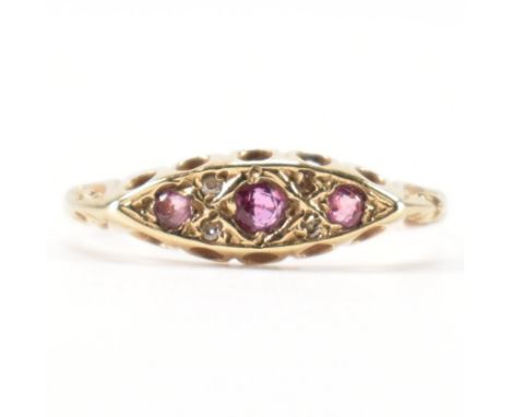 A hallmarked 9ct yellow gold, ruby &amp; diamond ring. The ring having a navette head set with three round cut rubies flanked