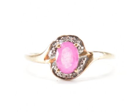 A hallmarked 9ct yellow gold, pink stone &amp; diamond crossover ring. The ring having a prong set oval cut pink stone surrou