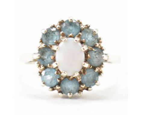 A hallmarked 9ct white gold, opal &amp; blue stone halo ring. The ring having a central oval opal cabochon surrounded by a ha