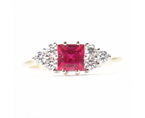 A hallmarked 9ct gold synthetic ruby and cubic zirconia CZ ring. The ring set with a square step cut synthetic ruby flanked b