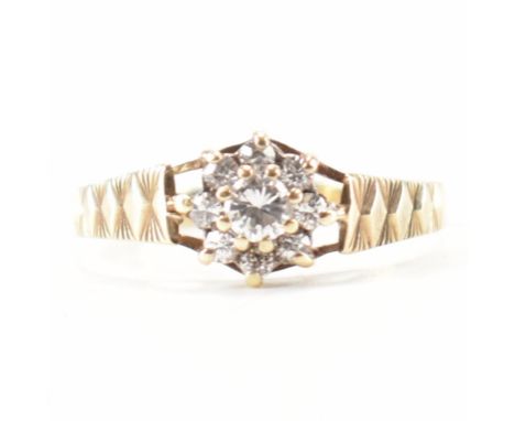 A hallmarked 9ct yellow gold &amp; CZ flower ring. The ring having a cluster of CZs in the form of a flower to a suspended ba