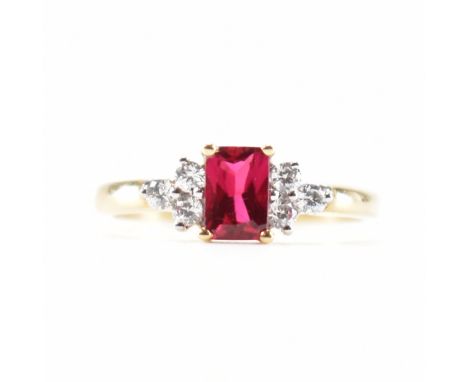 A hallmarked 9ct gold synthetic ruby and cubic zirconia CZ ring. The ring set with a mixed cut synthetic ruby flanked by thre