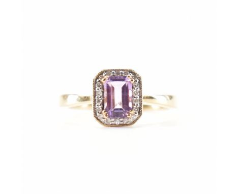 A hallmarked 9ct gold amethyst and diamond halo ring. The ring set with a step cut amethyst framed by a halo of round single 