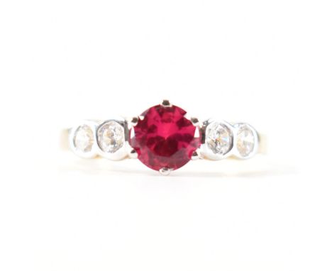 A hallmarked 9ct gold synthetic ruby and Cubic Zirconia CZ ring. The ring set with a mixed cut synthetic ruby flanked by two 