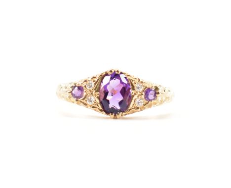 A hallmarked 9ct&nbsp; gold amethyst and diamond three stone ring. The ring set with a central oval cut amethyst flanked by f