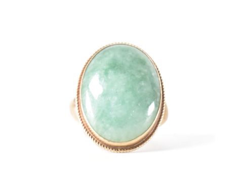 A hallmarked 9ct gold and jade cabochon ring. The ring set with a bezel set central jade cabochon framed by rope twist decora