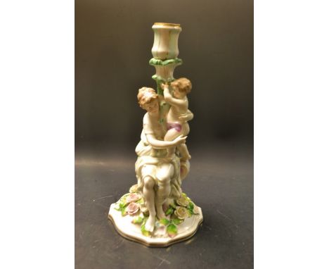 A late 19th century French porcelain figural candlestick, of a seated maiden and child, floral base, crossed batons mark (res