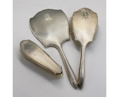 A matched George VI silver part dressing table set consisting of hand brush, clothes brush and mirror, all with engine turned