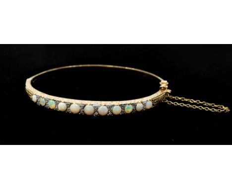 An opal and 9ct gold hinged bangle, comprising a row of round cabochon graduated opals to the tip, within diamond accents, wi