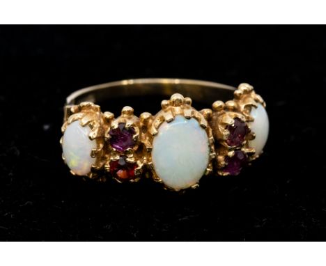 An opal and ruby set 9ct gold ring, comprising three graduated opals, with round mixed cut ruby accents, decorative mount, wi