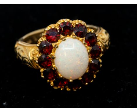 An opal and garnet 9ct gold cluster ring, comprising an oval opal within a border of round mixed cut garnets, setting width a