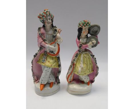 A pair of Victorian Staffordshire figures of musicians, he playing a mandolin, she playing cymbals, dressed in ermine trimmed