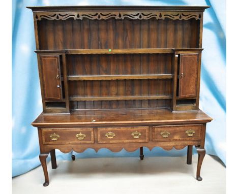 A solid English oak George III dresser with plate rack, three dresser drawers with brass swing handles, ornate carved apron, 