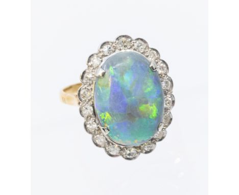 An opal and diamond set 18ct gold ring, comprising a solid oval opal to the centre aoprpx 15x12mm, within a border of small d
