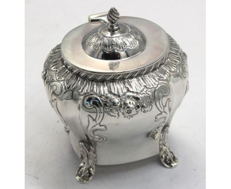 A late Victorian silver tea caddy, ogee shaped, foliate and floral chased decoration to upper section, scrolled supports, the