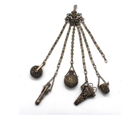 An early 20th century plated base metal chatelaine, having main clasp with cast foliate design with central mask and five loo