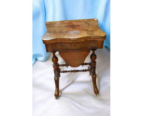 A Victorian ornate walnut fold over top sewing table with single frieze bobbin drawer, pull out wool compartment, standing on