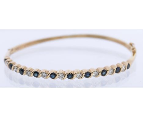 A diamond and sapphire 9ct  gold hinged bangle, the top set with ten round mixed cut sapphires, each approx 2.5mm, with nine 