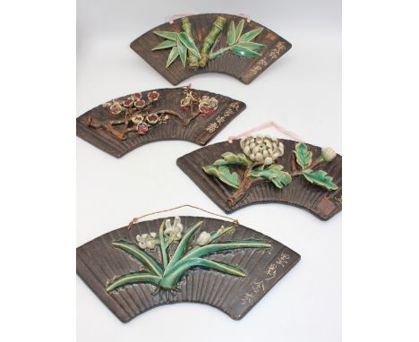 Four late 20th century Chinese pottery crescent shaped wall hanging plaques, with applied moulded floral decoration, incised 