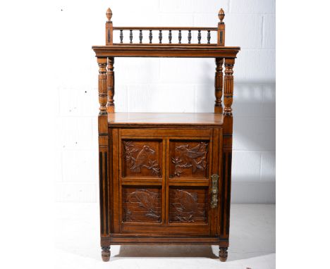 Aesthetic movement oak cabinet with carved panels, bobbin turned gallery back, above an open shelf, the cupboard door with fo