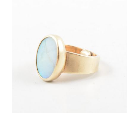 An opal dress ring, the oval cabochon cut stone, 14mm x 9mm, collet set in a 9 carat yellow gold mount with wide shank and sh