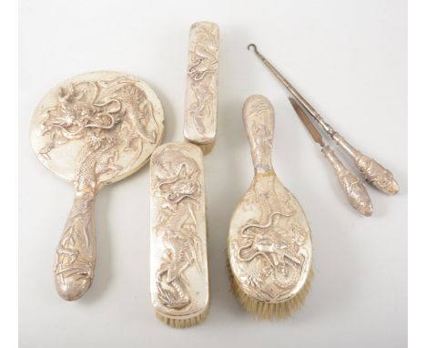 Chinese white metal four-piece dressing table set, embossed decoration of dragons, together with a similar button, hawk and f