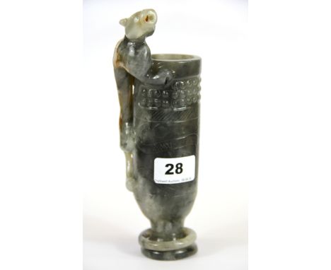 An unusual Chinese carved grey and white jade archaic form cup with a young dragon climbing up it and an integral ring to the