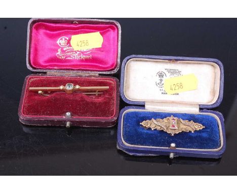 An Edwardian 9ct gold, ruby and seed pearl set bar brooch, sponsor WHC, gross weight 3.6g, 44mm; together with a 15ct gold, b