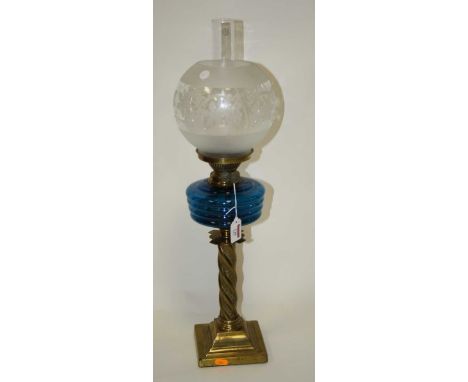 A Victorian pedestal oil lamp, having globular shade above a blue glass font, on a brass wythern moulded column and stepped s