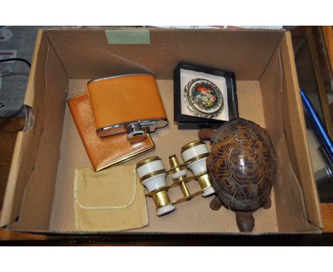 A box containing a collection of miscellaneous items to include a hip flask, compact, bell in the form of a tortoise etc