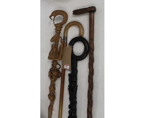 A North African ebonised totem style walking stick, carved with three figures in seated pose, with loop handle; together with