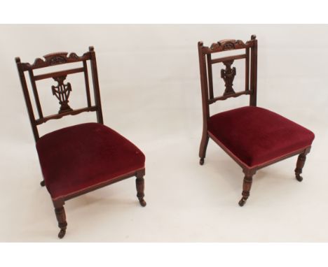 A pair of Edwardian carved walnut nursing chairs - the shaped, foliate carved top-rails over pierced vase splats and red stuf