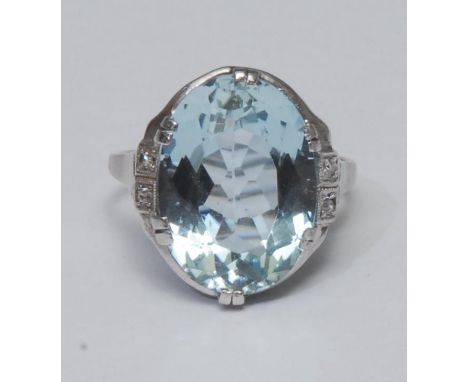 An aquamarine and diamond dress ring, large oval aquamarine approx 8.54ct, scrolling crest collar, six claw set above diamond